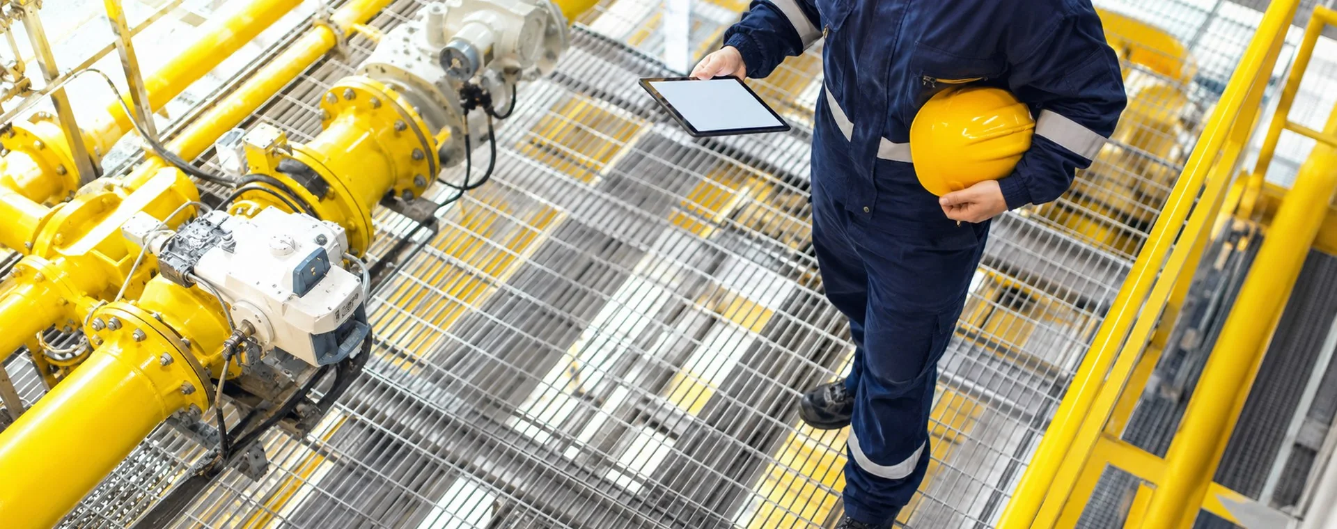 Utility worker on an industrial grated platform near pipework